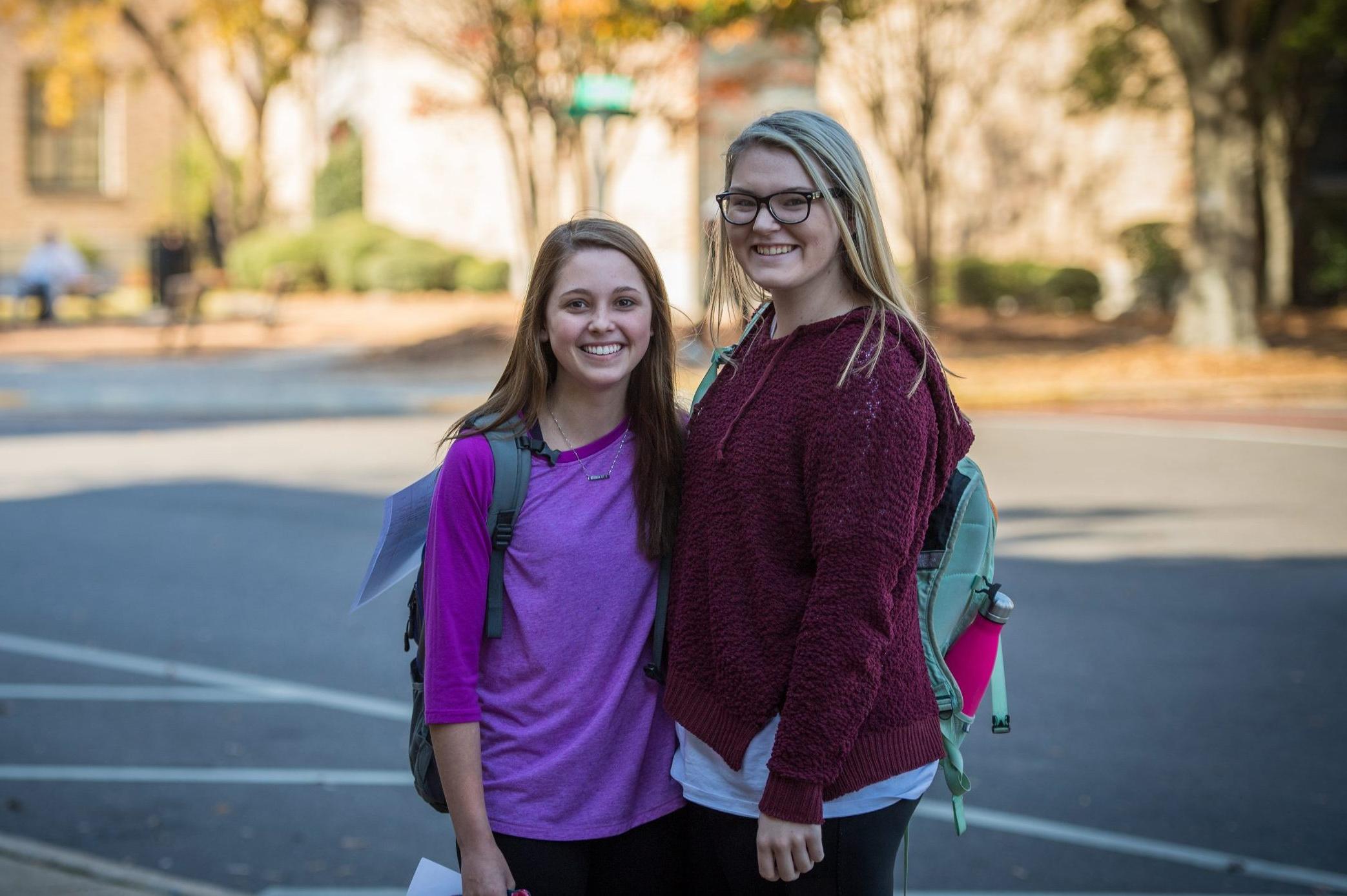 Two student walking to class and smiling.